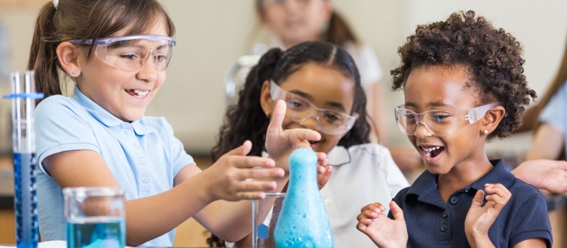 Excited girls using chemistry set together in elementary science classroom